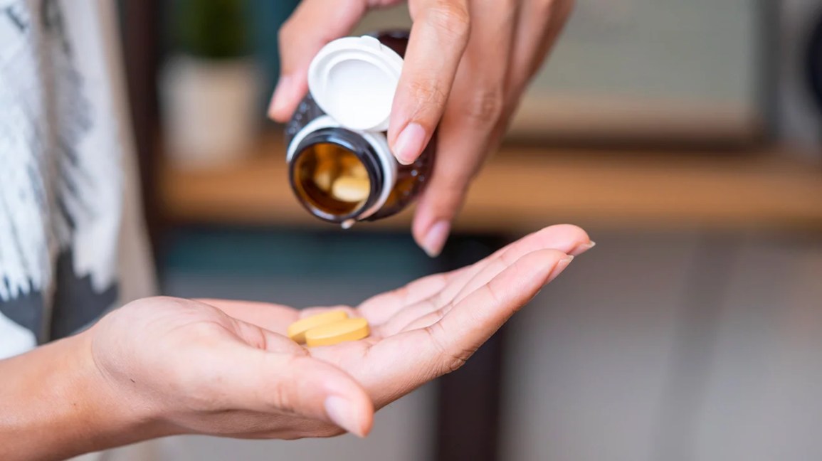 shaking pills onto palm from supplement bottle