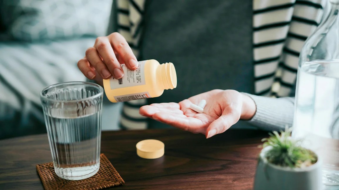 Woman shaking two pills into her hand